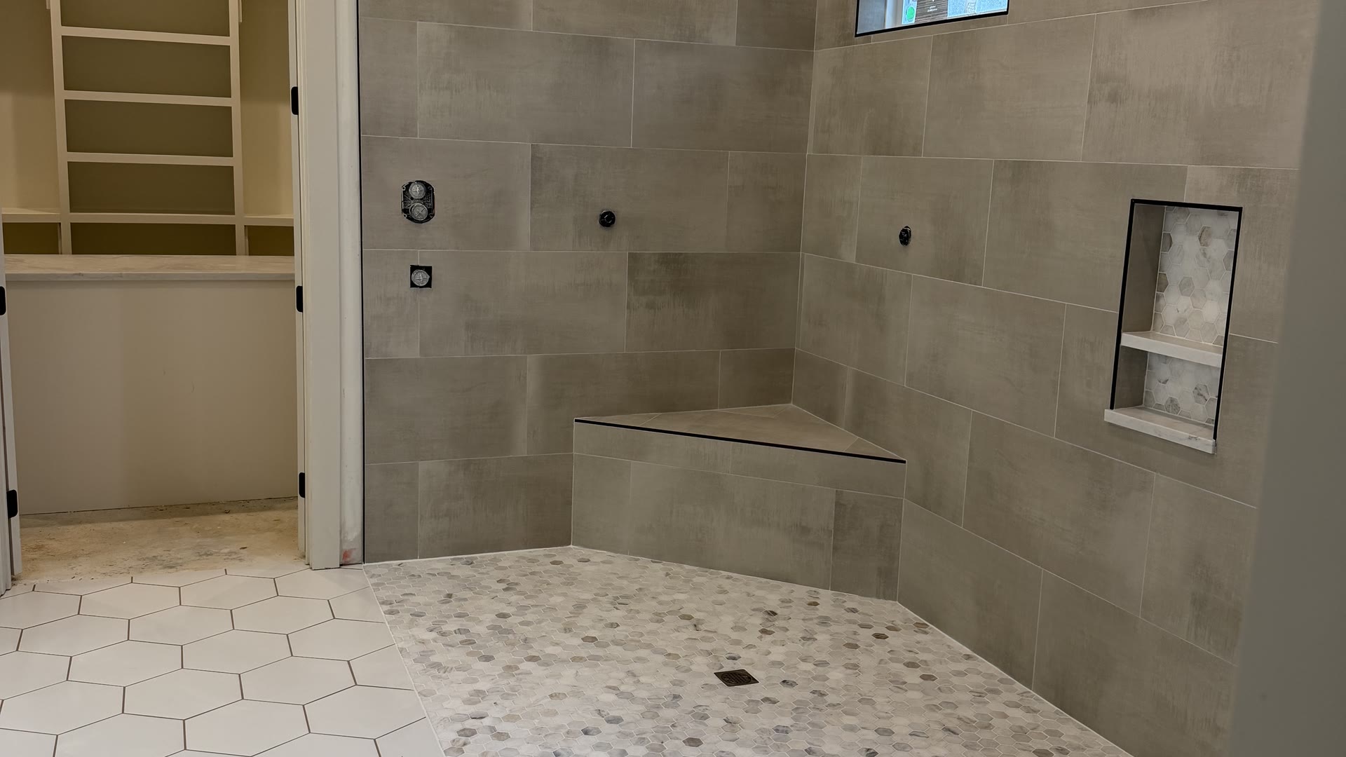 Curbless shower with a tiled bench, hex mosaic pan and a white hex tile floor